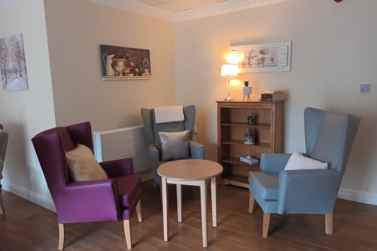 View of an additional lounge area at Alpine Lodge Care Home, featuring comfortable seating and a warm atmosphere for residents to socialise and relax.